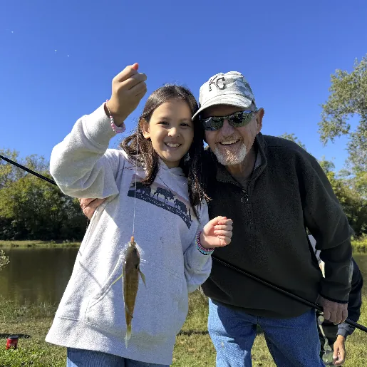 A girl and her grandfather showing off a fish at a Mission View fishing day